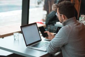 man on laptop and phone in cafe