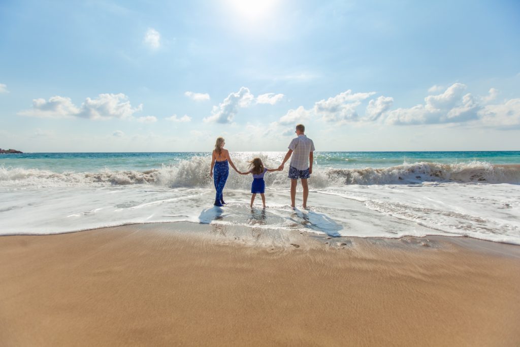 Family on the beach enjoy the waves from the sea