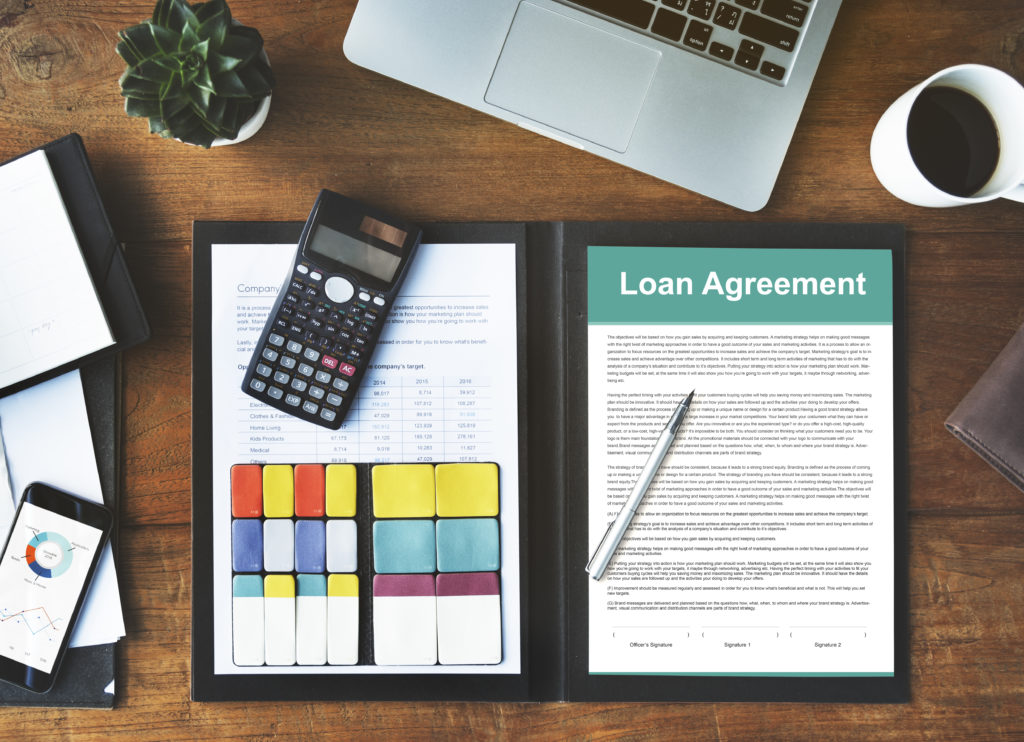 Loan agreement within a folder with calculator and pen on top