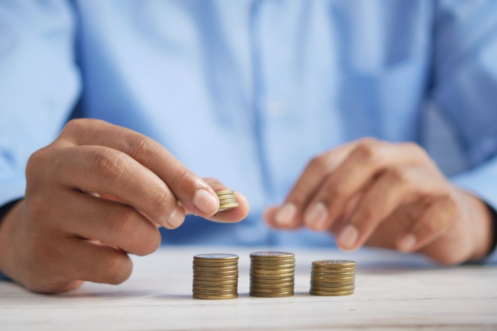 Man stacking coins on top of each other on table