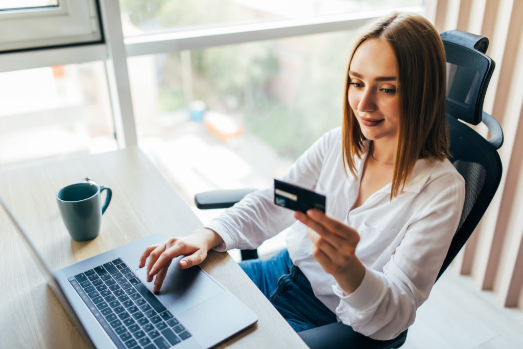 Woman using a credit card whilst on her laptop