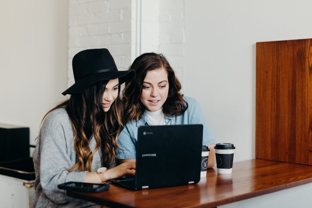 Two women booking a holiday on laptop together