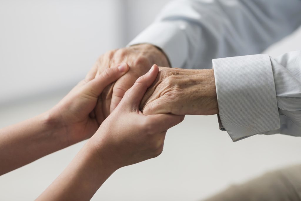 Person holding man's hands, showing moral support through debt problems.