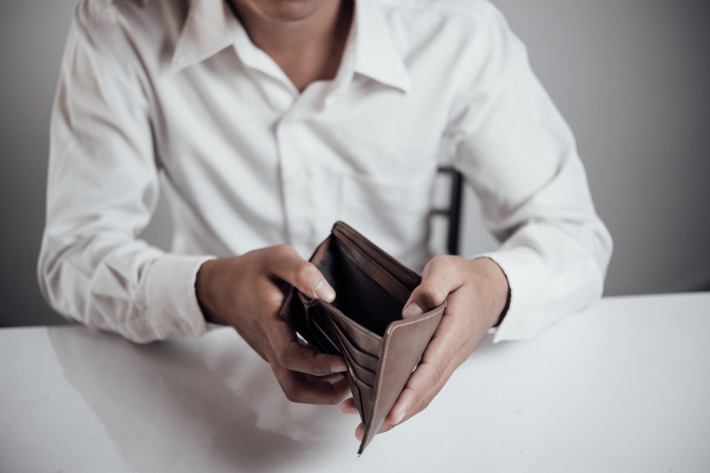 Man in debt holding an empty wallet