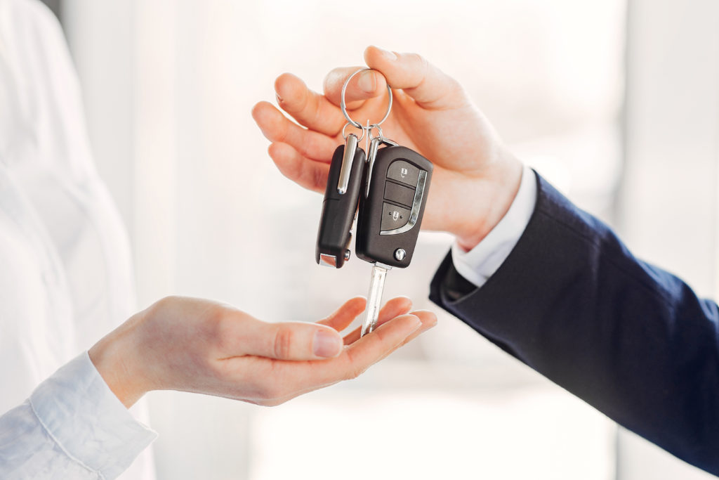 Man handing car keys to woman who has taken out a hire purchase loan for the vehicle
