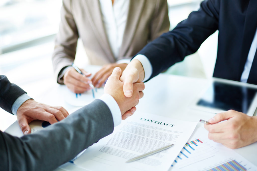 Man shaking hands with executives after agreeing a new contract for job